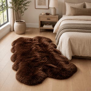May include: A dark brown, plush, faux fur area rug with an irregular, organic shape. The rug features a thick, shaggy texture and is positioned on a light-colored wooden floor in a bedroom setting, showcasing its soft, dense pile and deep color.