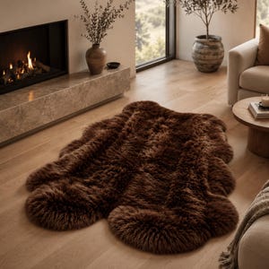 May include: A dark brown, plush, faux fur rug with an irregular, organic shape featuring a thick, shaggy texture. The rug is laid flat on a light-colored wooden floor, showcasing a deep, solid brown color throughout its entire surface area.