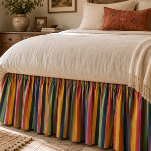 May include: A bed valance featuring a vibrant vertical striped pattern in shades of yellow, orange, pink, green, and blue. The fabric is gathered to create a ruffled effect along the base of the bed, providing a colourful accent to the bedding ensemble.