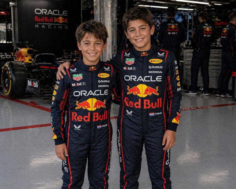 Op de afbeelding: Twee personen in bijpassende donkerblauwe Oracle Red Bull Racing team-overalls met rode en gele sponsorlogo's, waaronder Oracle, Red Bull, Honda en Tag Heuer, met een kleine Nederlandse vlag en de naam Max op de borst.