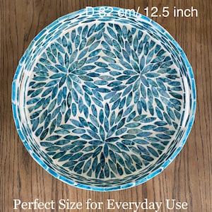 May include: A round decorative bowl with a mosaic design. The bowl is 32 cm in diameter and features a pattern of blue leaf-shaped tiles on a white background. The rim is a lighter shade of blue. The text "Perfect Size for Everyday Use" is at the bottom.