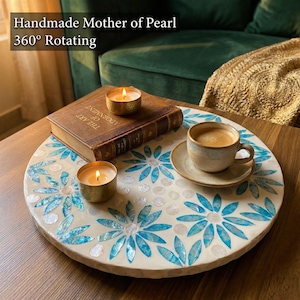 Könnte beinhalten: Eine weiße Keramik-Tasse mit schwarzem Henkel und dem Text "But First, Coffee" in schwarzer, handschriftlicher Schrift. Die Tasse steht auf einer weißen Oberfläche.