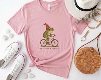 Off to Cause a Kerfuffle Frog Bicycle Tee, Whimsical Frog in Party Hat Print Pink Crew Neck Shirt for Quirky Style