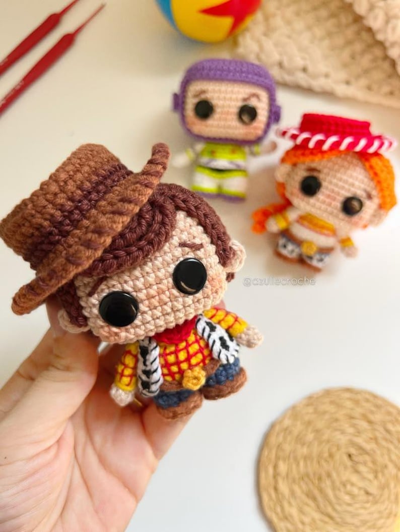 May include: Crocheted Toy Story character dolls, including Woody with a brown hat, Buzz Lightyear in a purple and green suit, and Jessie with a red hat. The dolls are handmade with detailed features and large black eyes.