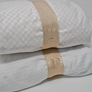 May include: Two white pillowcases with gold glitter trim and the letters "T" and "F" embroidered on the trim.