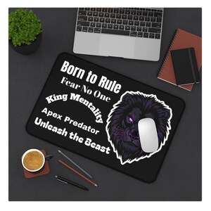 Può includere: Tappetino per mouse rettangolare nero con il testo "Born to Rule, Fear No One, King Mentality, Apex Predator, Unleash the Beast" e una grafica di leone viola. Un mouse bianco è sopra.