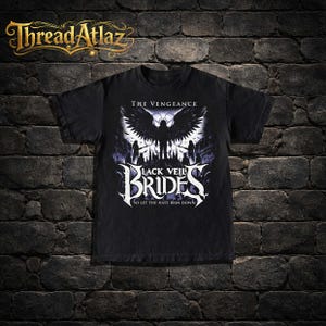 May include: Black t-shirt featuring a graphic design with the text "THE VENGEANCE" above a winged figure and the words "BLACK VEIL BRIDES" in a stylized font. The phrase "SO LET THE HATE RAIN DOWN" is below the band name.
