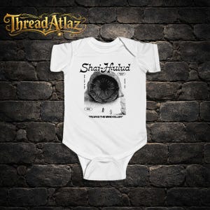 Puede incluir: Body de beb&eacute; blanco con un gr&aacute;fico en blanco y negro. El gr&aacute;fico presenta el texto "Shai-Hulud" sobre una ilustraci&oacute;n de una criatura parecida a un gusano. Debajo de la ilustraci&oacute;n est&aacute; el texto "FEAR IS THE MIND KILLER".