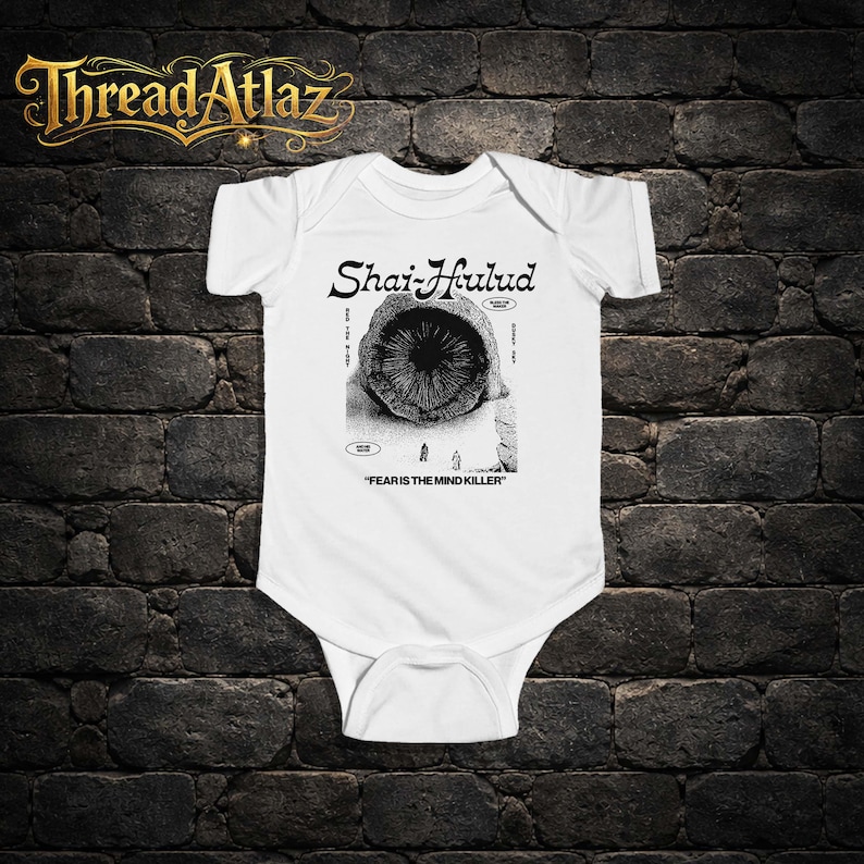 Puede incluir: Body de beb&eacute; blanco con un gr&aacute;fico en blanco y negro. El gr&aacute;fico presenta el texto "Shai-Hulud" sobre una ilustraci&oacute;n de una criatura parecida a un gusano. Debajo de la ilustraci&oacute;n est&aacute; el texto "FEAR IS THE MIND KILLER".