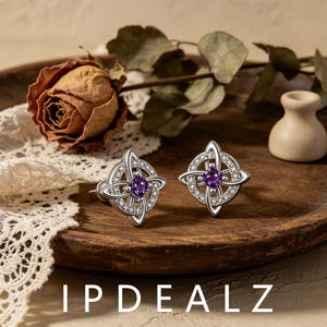 May include: A pair of silver stud earrings featuring a circular Celtic knot design encrusted with small clear stones and a central square-cut purple gemstone. The text IPDEALZ is visible at the bottom of the image.