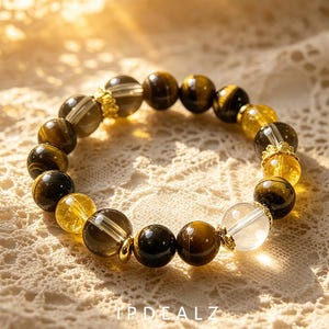 Pode incluir: Uma pulseira de contas com pedras redondas alternadas de olho de tigre, quartzo transparente e citrino amarelo. As contas são intercaladas com pequenos espaçadores de metal dourado ornamentados. O texto IPDEALZ está impresso em branco.