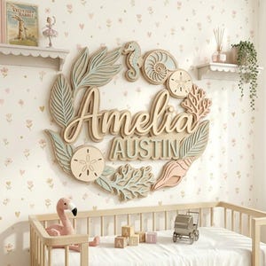 Könnte beinhalten: Wanddekoration aus Holz mit den Namen "Amelia" und "Austin" in einem mehrschichtigen Design. Das Design umfasst Seepferdchen-, Muschel- und Blattelemente in Pastellfarben. Die Dekoration ist auf einer floralen Tapete angebracht.