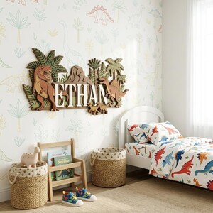 Puede incluir: Decoraci&oacute;n de pared de madera con tem&aacute;tica de dinosaurios con el nombre "ETHAN" en letras blancas. La decoraci&oacute;n presenta un T-Rex, un Spinosaurus y otros dinosaurios, junto con palmeras y monta&ntilde;as. La habitaci&oacute;n tiene un juego de cama y papel pintado con tem&aacute;tica de dinosaurios.
