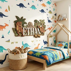 Puede incluir: Dormitorio infantil con tem&aacute;tica de dinosaurios. Cama de madera, edred&oacute;n con dise&ntilde;os de dinosaurios y pegatinas de pared. Una cesta de mimbre contiene juguetes de dinosaurios de peluche. El nombre "ETHAN" est&aacute; en un letrero de madera.