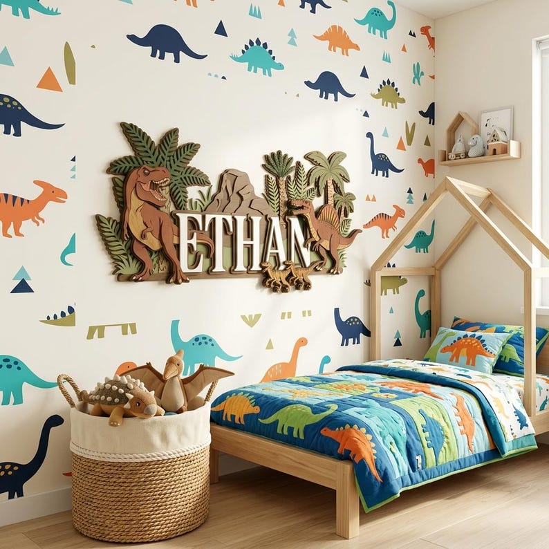 Puede incluir: Dormitorio infantil con tem&aacute;tica de dinosaurios. Cama de madera, edred&oacute;n con dise&ntilde;os de dinosaurios y pegatinas de pared. Una cesta de mimbre contiene juguetes de dinosaurios de peluche. El nombre "ETHAN" est&aacute; en un letrero de madera.