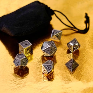 May include: A set of metallic dice with gold accents and a black drawstring bag. The dice are in various geometric shapes, including a cube, a d20, and a d4. The numbers are etched in a dark color, and the dice are on a gold surface.