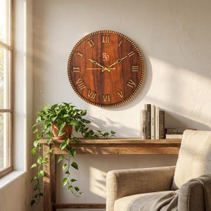 Peut inclure: Une grande horloge murale ronde en bois avec des chiffres romains et des aiguilles dorées. L'horloge a un cadran en bois foncé et une bordure décorative texturée. L'horloge est fixée sur un mur de couleur claire.