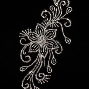 Könnte beinhalten: Ein dekoratives Bügelbild mit einem Blumenmotiv, das aus zahlreichen kleinen, klaren, reflektierenden Strasssteinen besteht, die in einem wirbelnden, organischen Muster auf einem einfarbigen schwarzen Hintergrund angeordnet sind und einen funkelnden Effekt erzeugen.