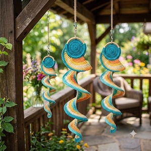 Può includere: Tre ornamenti a spirale sospesi realizzati in filato lavorato all'uncinetto nei toni del verde acqua, arancione e crema. Ogni pezzo presenta una parte superiore circolare fissata a un anello di legno, appesa a un filo con una perlina.