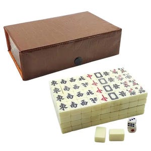 Peut inclure: Un jeu de Mahjong complet avec des tuiles ivoire portant des caractères et symboles chinois. L'ensemble comprend un étui en similicuir marron, deux dés et des tuiles supplémentaires. Les tuiles sont empilées, prêtes à jouer.
