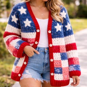 May include: A crochet cardigan in red, white, and blue, featuring star and stripe patterns. The open front sweater has a V-neck, flower-shaped buttons, and long sleeves. The design evokes the American flag.