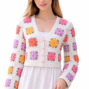 May include: A set of three ceramic mugs with a speckled, cream-colored glaze. Each mug features a different hand-painted design: a blue and green leaf, a yellow flower, and a red berry. The mugs have a simple, rounded shape.