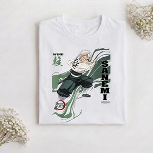 Puede incluir: Camiseta blanca con un gr&aacute;fico de un personaje de anime con cabello blanco, empu&ntilde;ando una espada. El dise&ntilde;o incluye el texto "WIND" en negro, caracteres japoneses y el nombre "SANEMI" en letras negras verticales. La camiseta tambi&eacute;n tiene el logo de "Demon Slayer".