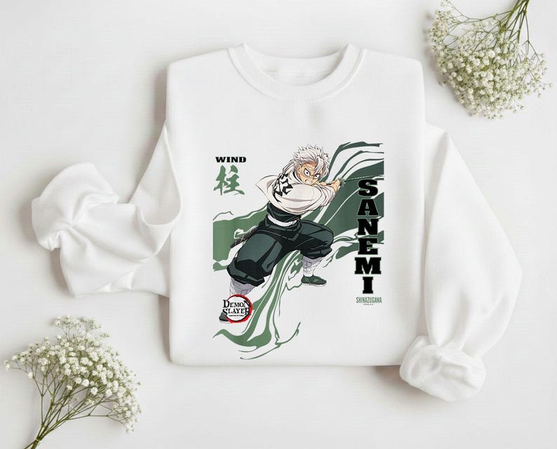 Puede incluir: Sudadera blanca con un gr&aacute;fico de un personaje de anime, Sanemi, en acci&oacute;n con el texto "WIND" y "SANEMI". El dise&ntilde;o incluye acentos verdes y negros, y el logo "Demon Slayer".
