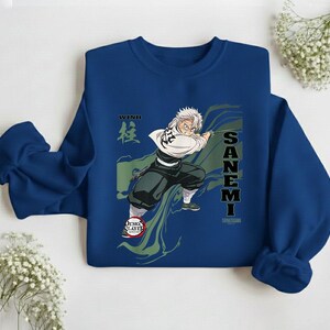 Puede incluir: Una sudadera azul marino con un gr&aacute;fico de un personaje de anime. El personaje tiene el pelo blanco y sostiene una espada. La sudadera tiene el texto "WIND" y "SANEMI" en blanco.