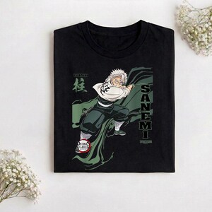 Puede incluir: Camiseta negra con un gr&aacute;fico de un personaje de anime con pelo blanco y una capa verde. El texto "SANE MI" y caracteres japoneses est&aacute;n en la camiseta. El logo de Demon Slayer tambi&eacute;n es visible.