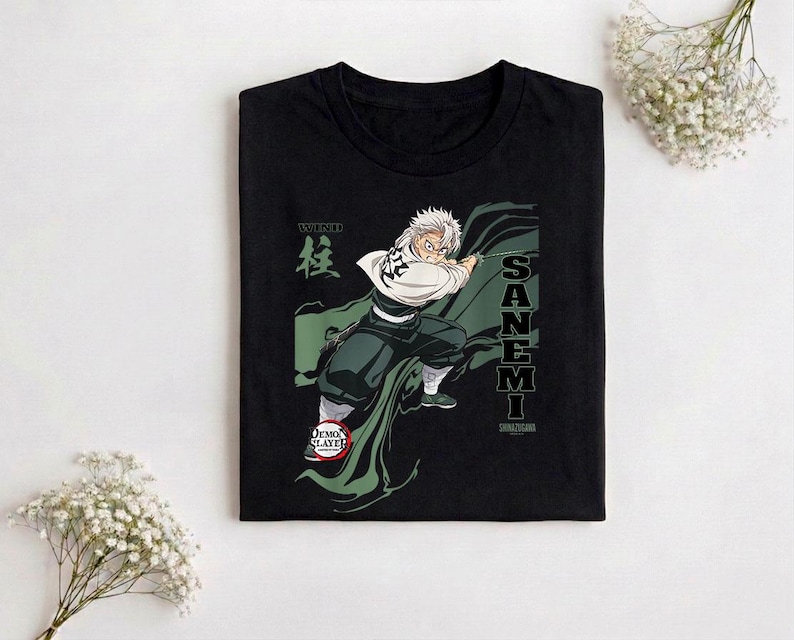Puede incluir: Camiseta negra con un gr&aacute;fico de un personaje de anime con pelo blanco y una capa verde. El texto "SANE MI" y caracteres japoneses est&aacute;n en la camiseta. El logo de Demon Slayer tambi&eacute;n es visible.