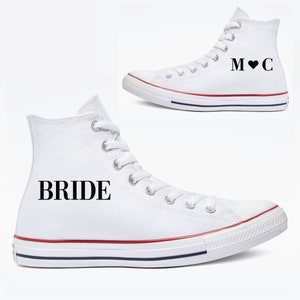 May include: A pair of white high-top sneakers with black text. One shoe says "BRIDE" and the other says "M♥C".