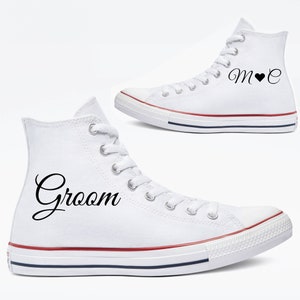 May include: White high-top sneakers with black text that reads "Groom" on one shoe and "M ♥ C" on the other. The sneakers have red and blue stripes on the soles.