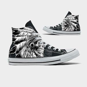 May include: Black high-top sneakers with a white sole and laces. The sneakers feature a detailed black and white graphic of a Native American headdress and skull design on the side.