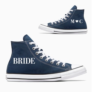 May include: A pair of navy blue high-top sneakers with white laces. One shoe says "BRIDE" and the other says "M♥C".
