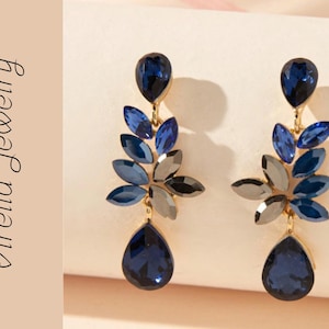 Orecchini pendenti con cristalli blu e motivo floreale dorato.