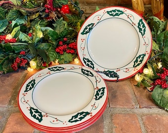 May include: Set of four white ceramic dinner plates with a green holly leaf and red berry border.
