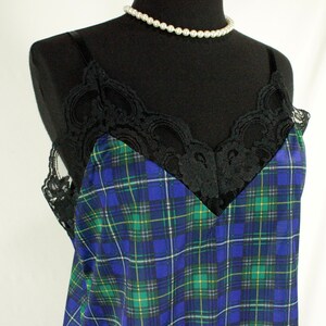 May include: A blue and green plaid satin slip with black lace trim. The slip has a V-neckline and thin straps.