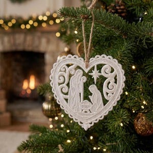 May include: A white heart-shaped Christmas ornament made of intricate lace embroidery. The design features a nativity scene with figures surrounding a manger and a star above, all enclosed within a scalloped border, suspended by a brown twine loop.