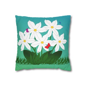 Op de afbeelding: Een decoratief vierkant kussen met een bloemenontwerp. Het kussen heeft een teal- tot groenverloopachtergrond met witte bloemen, groene bladeren en kleurrijke vlinders. De bloemen hebben gele centra.