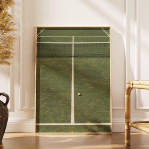 May include: A rectangular wall art print featuring a top-down view of a green tennis court with white boundary lines, a dark green net, and a single yellow tennis ball resting on the surface, all enclosed within a light-coloured wooden frame.