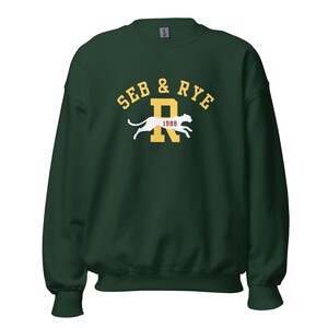 May include: A dark green sweatshirt with the text "SEB & RYE" in yellow arched above a yellow "R" with a white panther silhouette and the year "1988" in white. The sweatshirt has a crew neck and long sleeves.