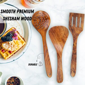 K&ouml;nnte beinhalten: Drei K&uuml;chenutensilien aus Holz: ein Sch&ouml;pfl&ouml;ffel, ein fester L&ouml;ffel und ein Pfannenwender. Die Utensilien sind aus Sheshamholz gefertigt und haben eine glatte Oberfl&auml;che. Der Text "SMOOTH PREMIUM SHESHAM WOOD" steht oben. Das Wort "DURABLE" ist ebenfalls sichtbar.