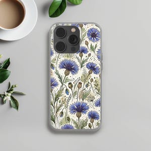 May include: Clear phone case featuring a floral pattern of blue cornflowers and green leaves on a cream background. The case has a clear border and a camera cutout. The design is a watercolor style.