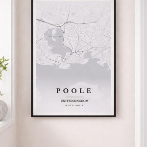 Pode incluir: Impressão emoldurada a preto e branco de um mapa de Poole, Reino Unido. O nome "POOLE" é exibido no centro, com coordenadas abaixo. O mapa detalha a rede rodoviária e a costa. A moldura é preta.