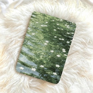 May include: A rectangular tablet case featuring a high-resolution print of green water with gentle ripples and scattered white flower petals. The surface of the case is smooth and glossy, displaying a detailed nature-inspired pattern across the front.