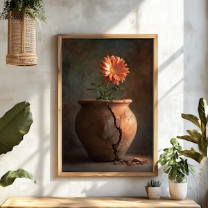 May include: A framed artwork showing an orange flower in a cracked terracotta pot. The artwork is set against a neutral background, with a wooden bench and potted plants in the foreground. The artwork is framed in a light brown wooden frame.