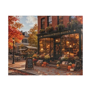 May include: A jigsaw puzzle depicting a bookstore named Maple & Main Books with a brick facade, large windows, and autumn decor including pumpkins and flowers. A sidewalk sign reads Books Stories Coffee Welcome, with a coffee cart nearby.