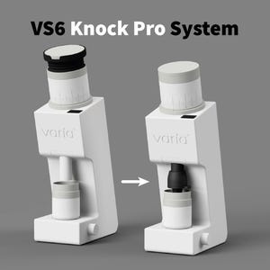 Könnte beinhalten: Eine weiße VS6 Knock Pro System Kaffeemühle mit einem schwarz-weißen Deckel und einem kleinen weißen Behälter. Das Wort "varia" ist auf der Seite aufgedruckt. Das Bild zeigt die Mühle mit und ohne den Behälter.