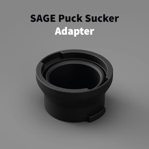Könnte beinhalten: Schwarzer Adapter mit dem Text "SAGE Puck Sucker Adapter" in Weiß. Der Adapter hat eine zylindrische Form mit breitem Sockel und vertieftem Innenraum. Er ist für ein bestimmtes Gerät konzipiert.